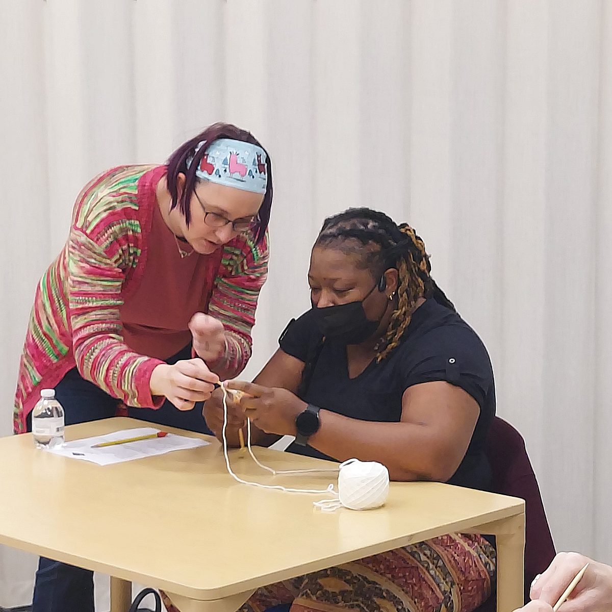 woman instructor helping woman learn how to knit
