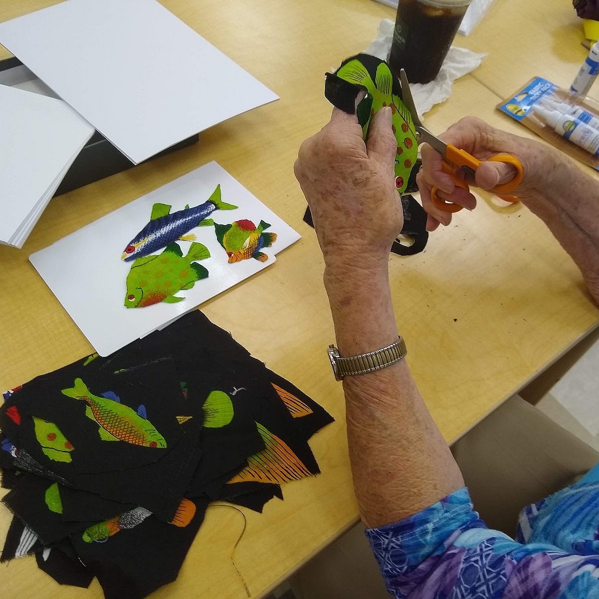woman cutting and pasting pictures of colorful fish