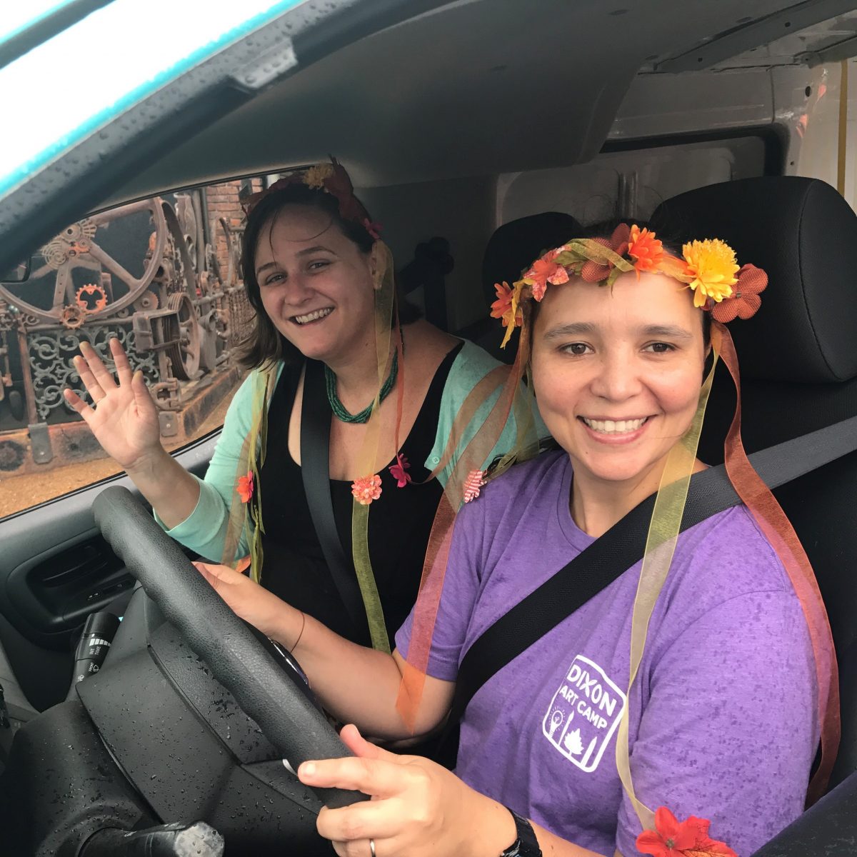 two woman driving a van, one in a flower crown