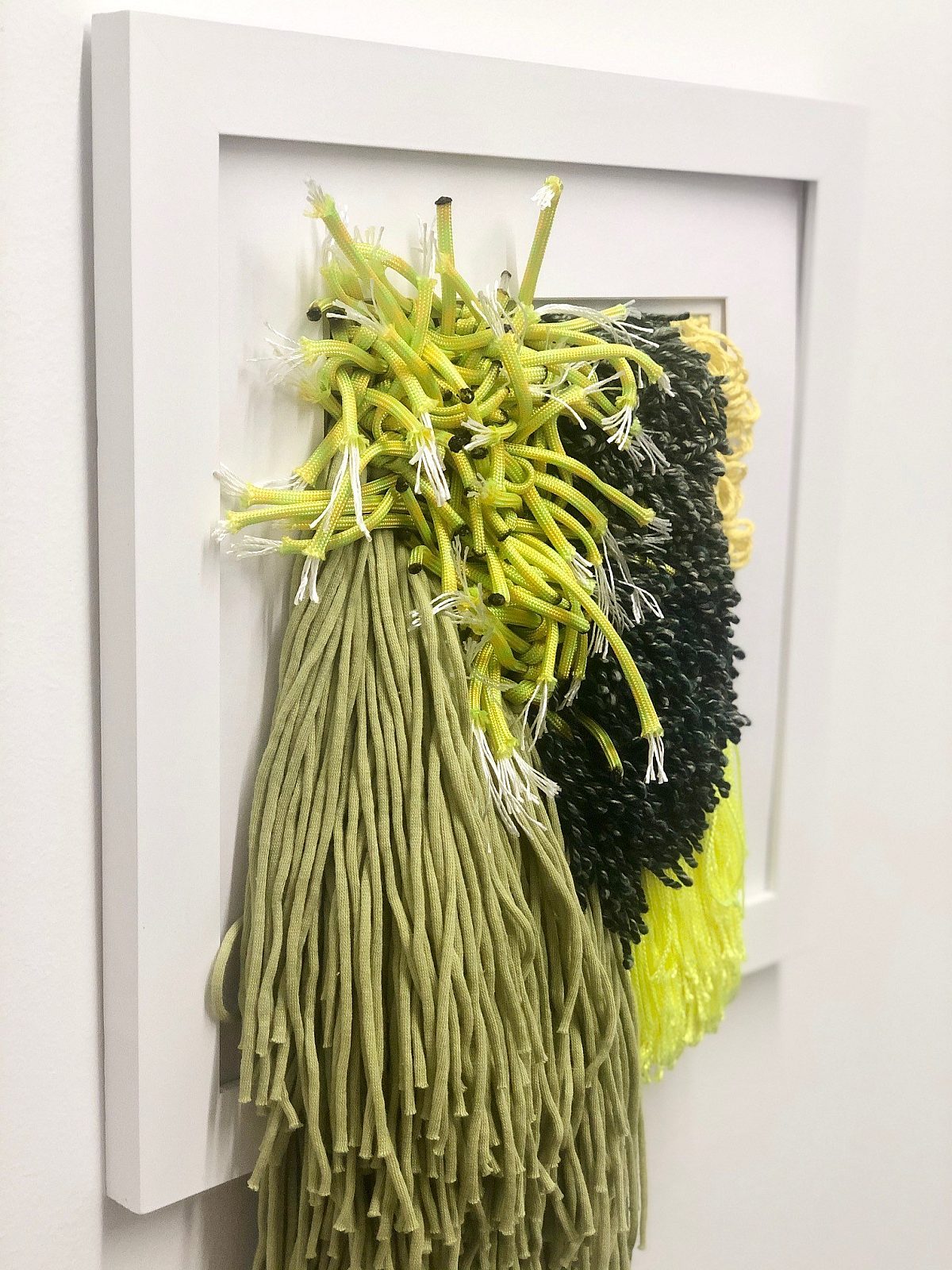 shades of green and yellow, textile art hanging in white frame on the wall