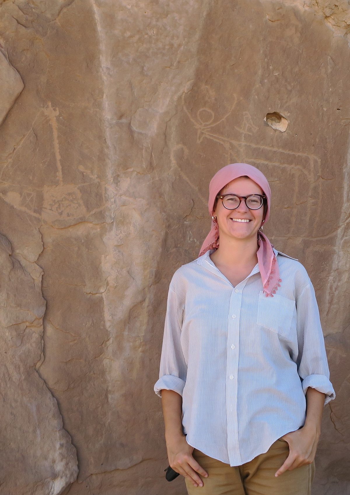 Woman, names Darcy smiling in front of a wall