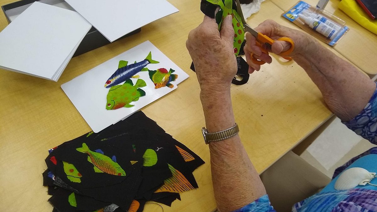 woman cutting and pasting pictures of colorful fish