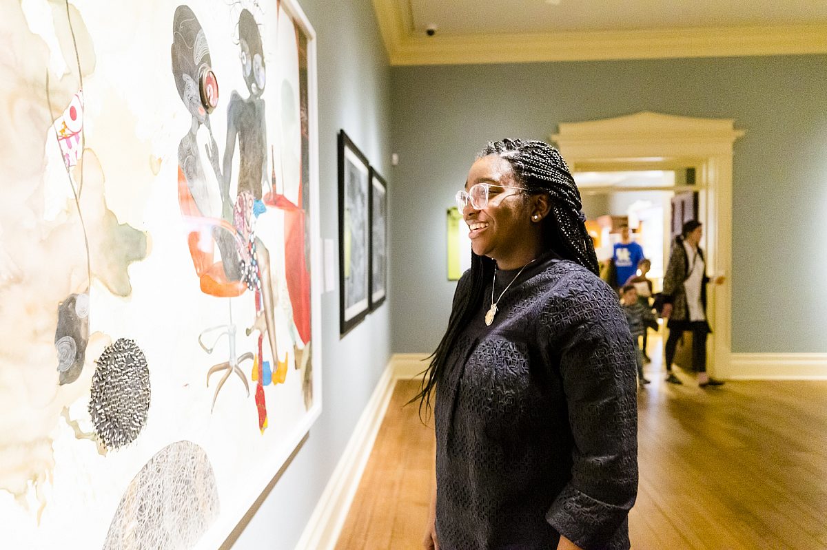 woman smiling and looking at large painting in gallery
