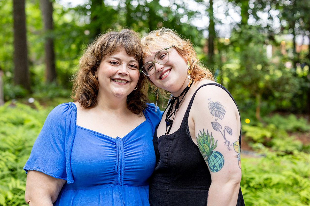 two women smiling in gardens, blue and black clothing