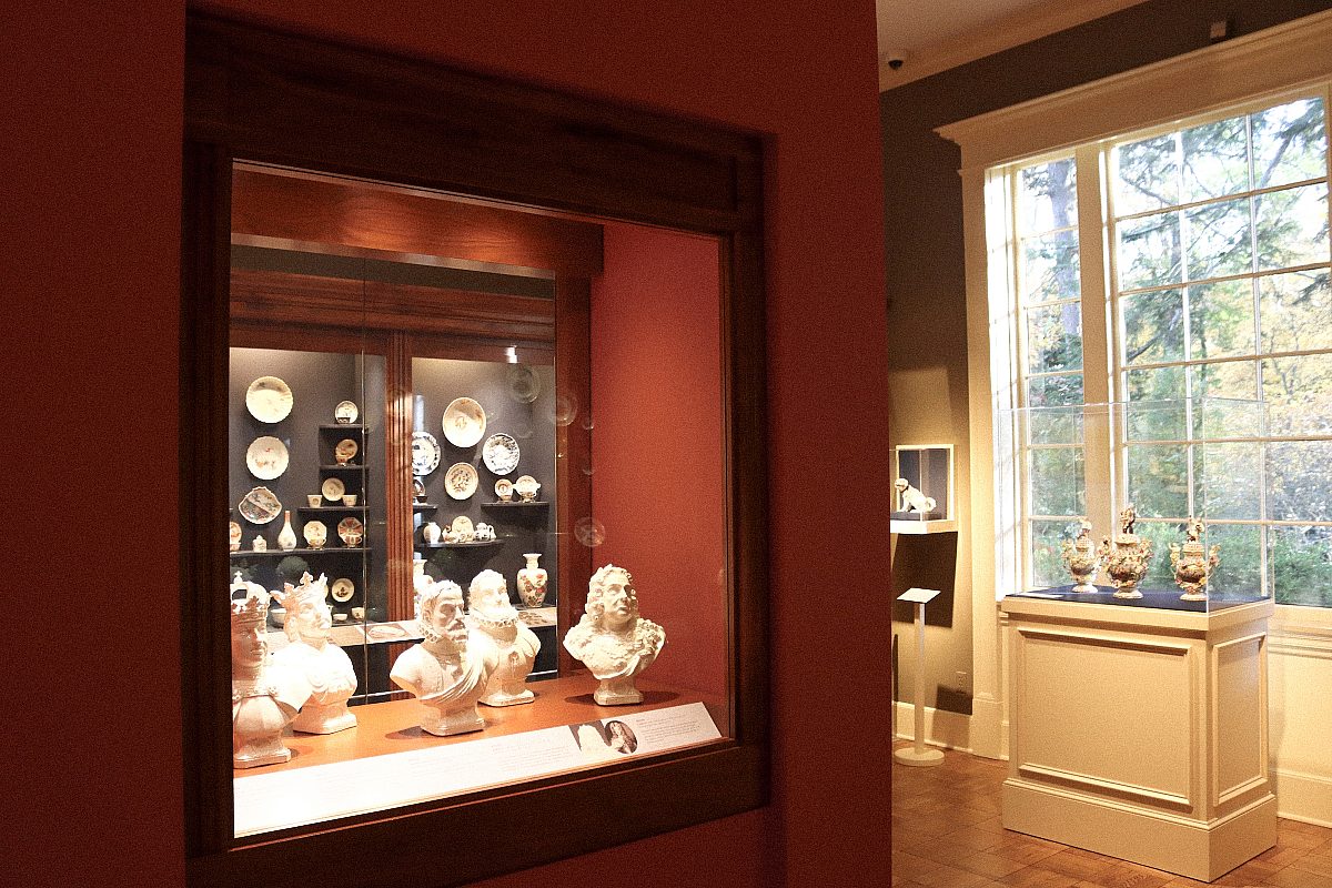 angled red wall with busts and porcelain plates behind display case