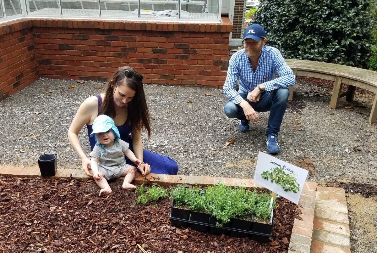 family with baby sitting in learning garden