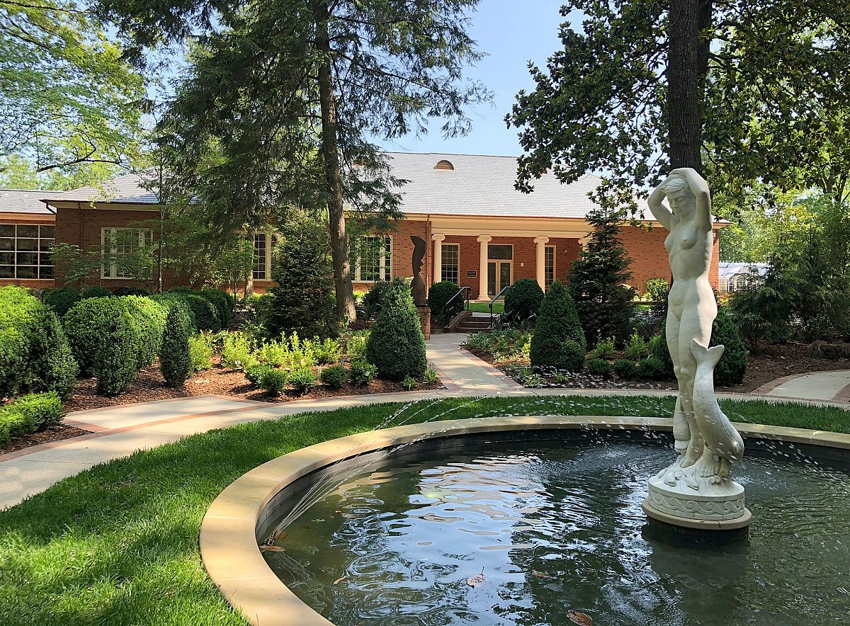 gardens outside education building with circular fountain containing white statue of a human and leaping fish