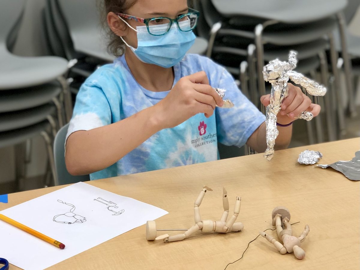 young girl making armature doll out of tin foil