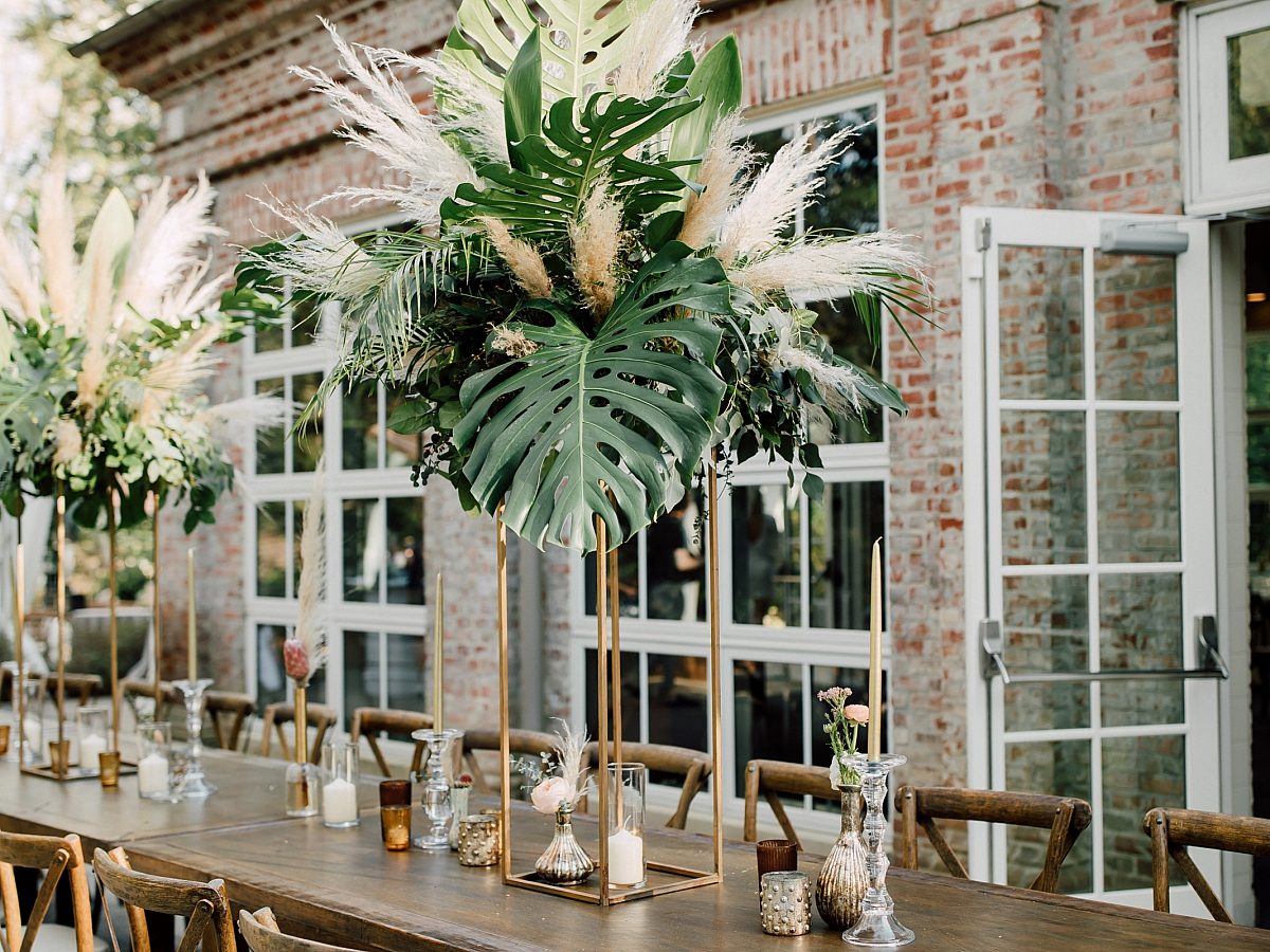 Wedding table decorated with candles and hanging white flowers in front of glass windows