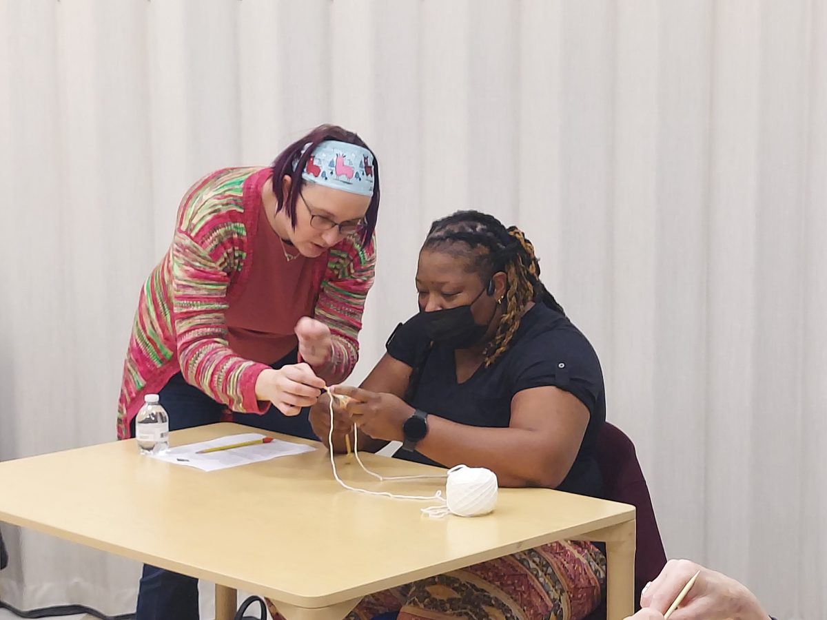 woman instructor helping woman learn how to knit