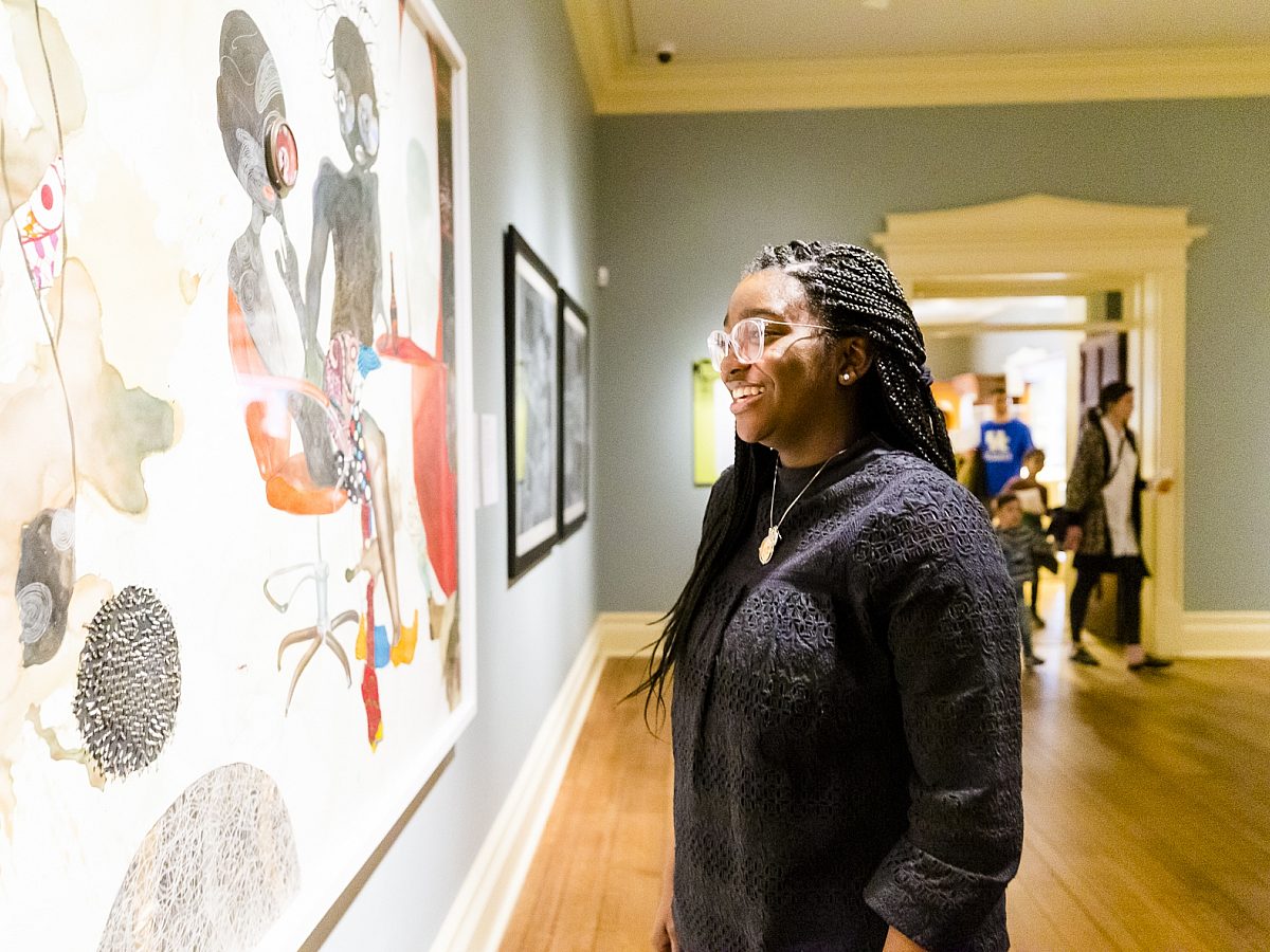 woman smiling and looking at large painting in gallery