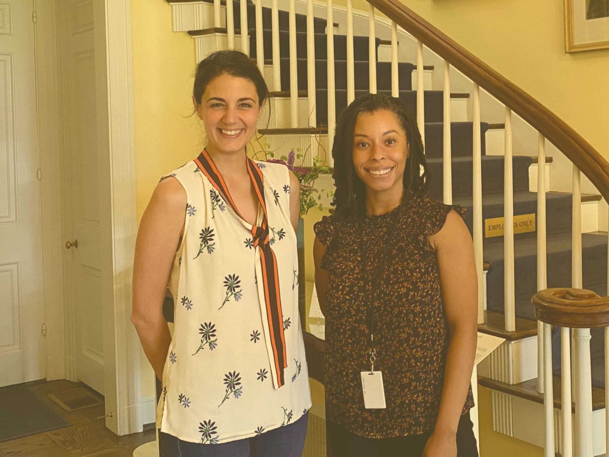 square photo with yellow tint, two women standing in front of dixon residence staircase