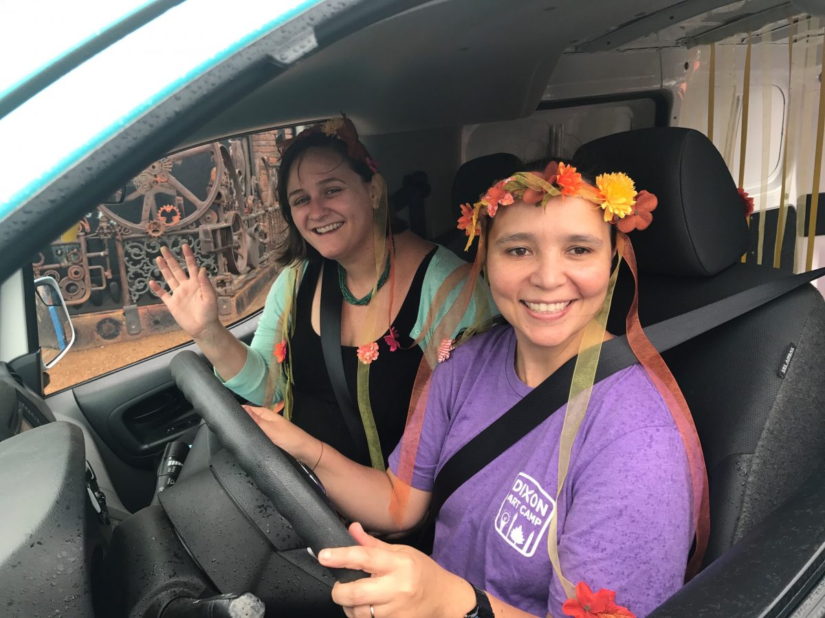 two woman driving a van, one in a flower crown