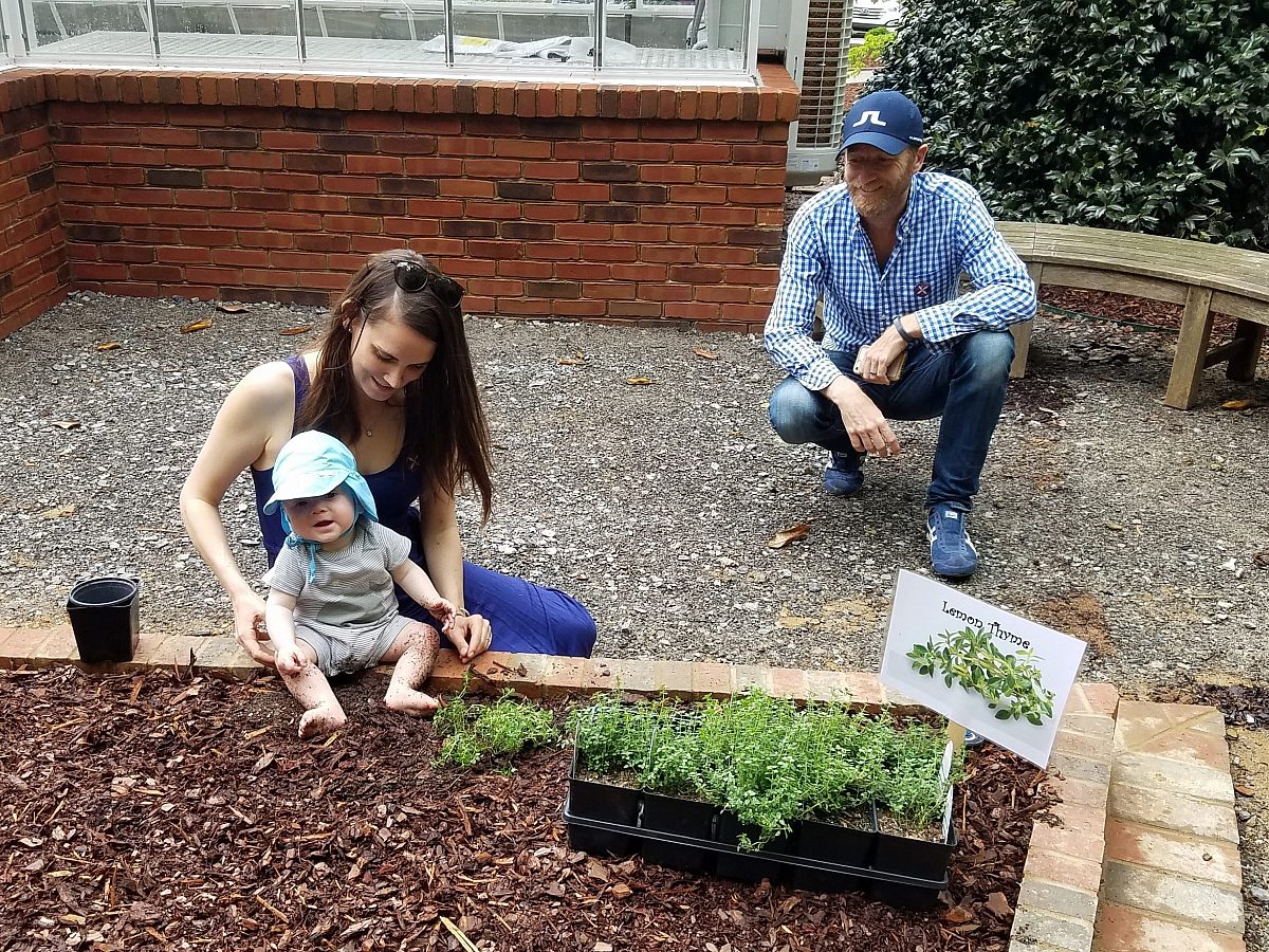 family with baby sitting in learning garden