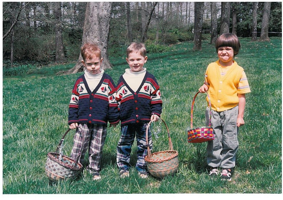 vintage photo of two matching kids and one kid with bowl cut holding easter baskets outside