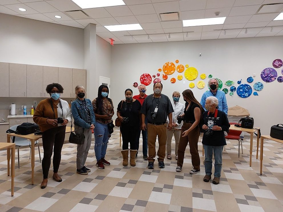 group of masked adults posing for photo in classroom
