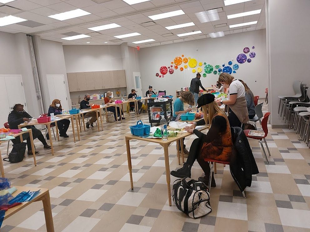 adults at individual tables in classroom working on art activities