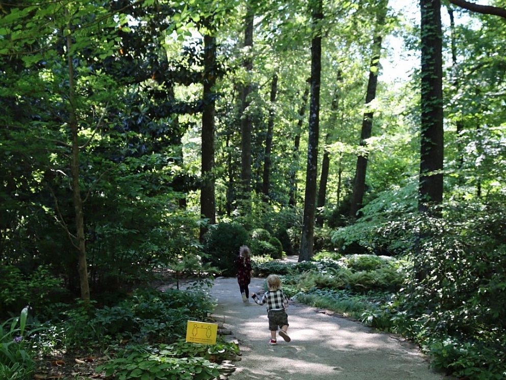 children running along gravel path through wooded gardens