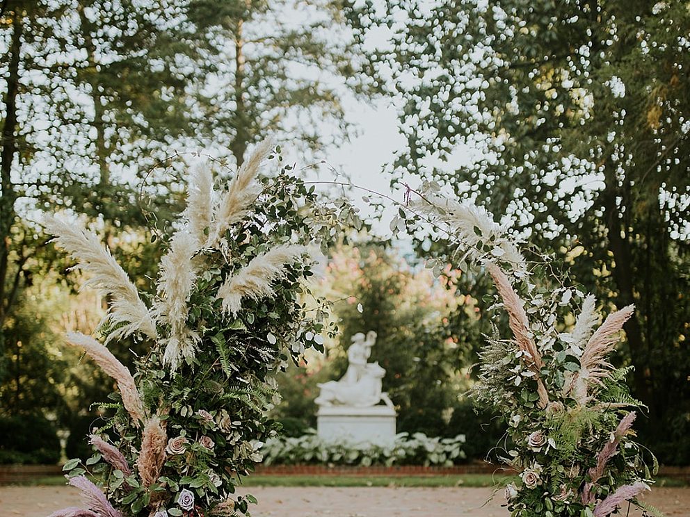 wedding arch of white flowers, roses, and greenery in front of steps in the garden
