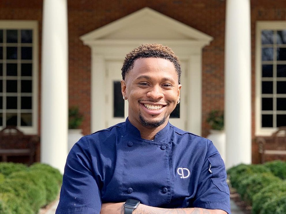 chef phillip stands smiling in blue chef's shirt, arms crossed, outside of museum entrance