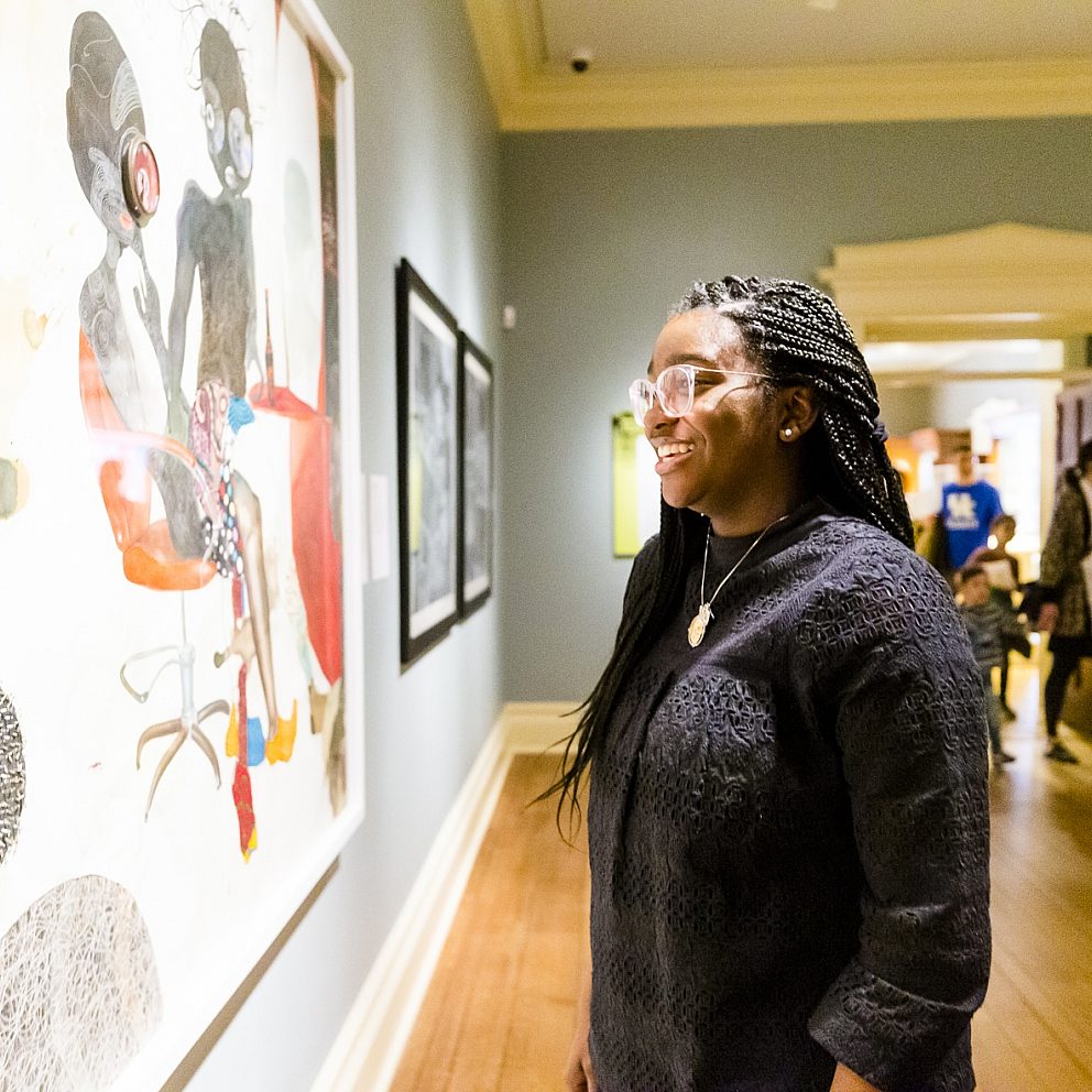 woman smiling and looking at large painting in gallery